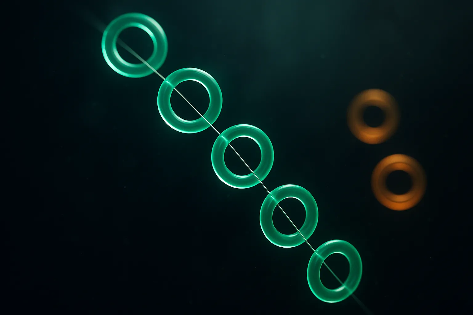 Five linked emerald rings descending in a chain, two unlinked gold rings adrift